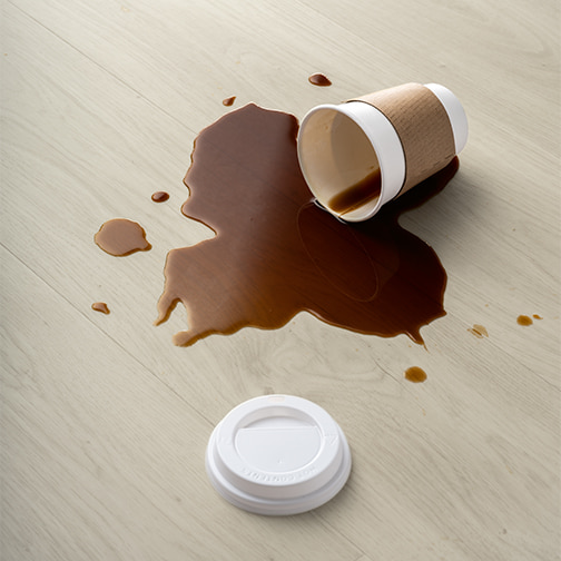 spildt kaffe på gråt Rigid-vinylgulv fra Pergo